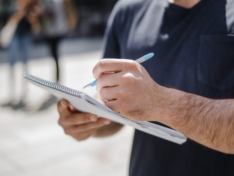 man-holding-notebook-writing